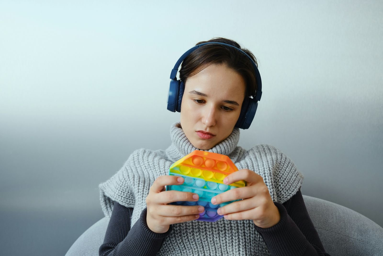A teenager with headphones focuses on a sensory fidget toy